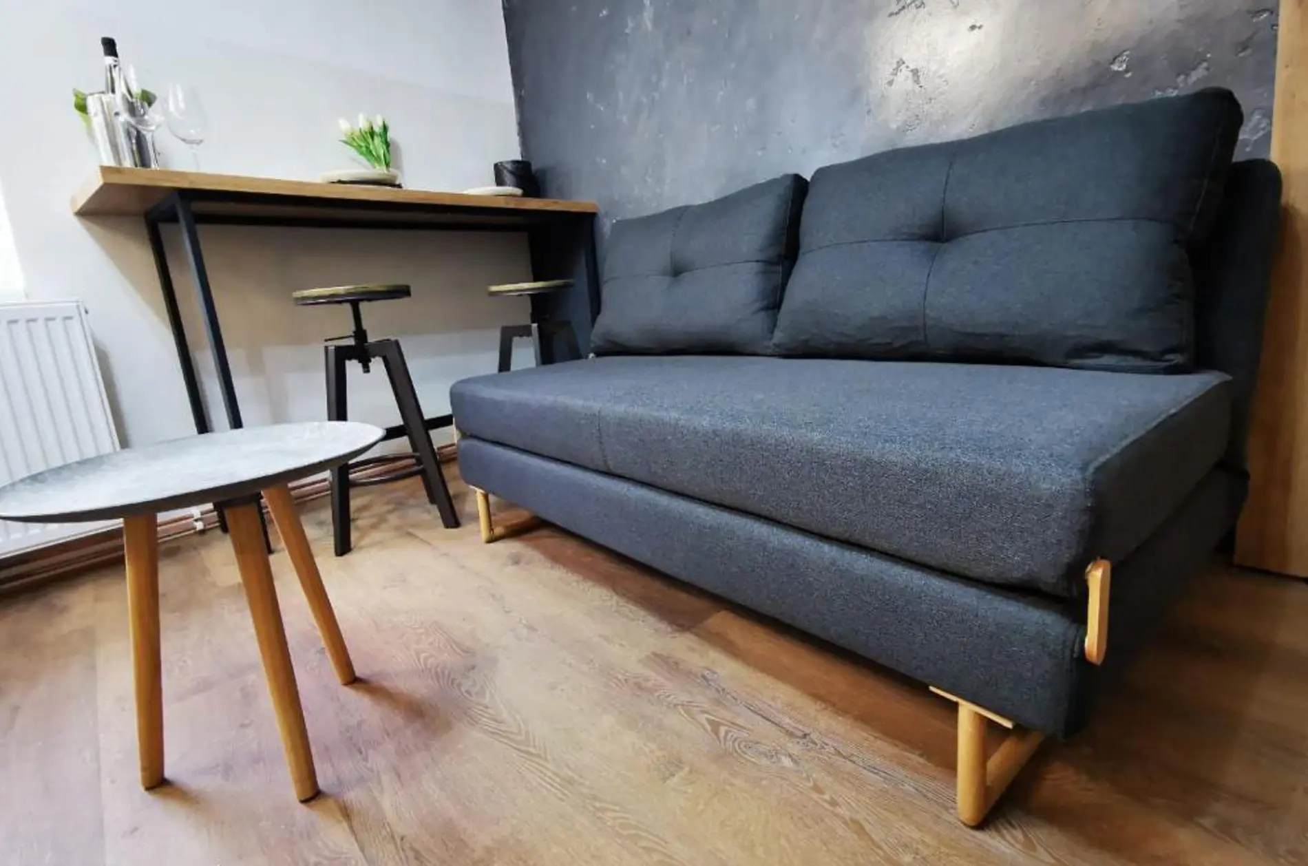 Stylová moderní pohovka v apartmánu s elegantním designem a barovým pultem v pozadí.